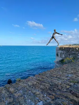 a statue of a man jumping off the edge of a cliff at Bord de mer, terrasse, tout à pieds in Cannes