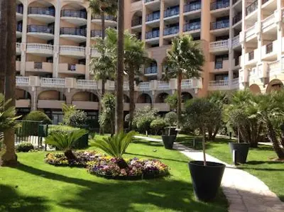 a large building with palm trees and plants in a park at Bord de mer, terrasse, tout à pieds in Cannes