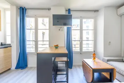 a living room with a kitchen with blue curtains at Studio centre Cannes in Cannes