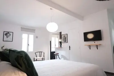 a white bedroom with a bed and a tv on the wall at Studio Cannes - 5mn Palais des Festivals (400m) in Cannes