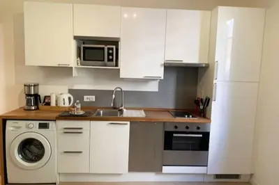 a kitchen with white cabinets and a sink and a dishwasher at Le Canada - 2Pièces Croisette plage derrière le Carlton calme in Cannes
