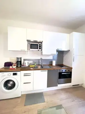 a kitchen with white cabinets and a sink and a microwave at Le Canada - 2Pièces Croisette plage derrière le Carlton calme in Cannes