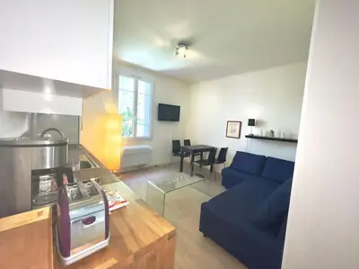 a living room with a blue couch and a kitchen at Le Canada - 2Pièces Croisette plage derrière le Carlton calme in Cannes