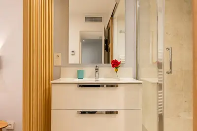 a white bathroom with a sink and a shower at Upscale 3-room apartment 300m from the beaches in Cannes