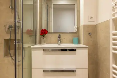 a bathroom with a sink and a mirror and a shower at Upscale 3-room apartment 300m from the beaches in Cannes