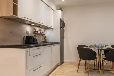 a kitchen with white cabinets and a table with chairs at Upscale 3-room apartment 300m from the beaches in Cannes