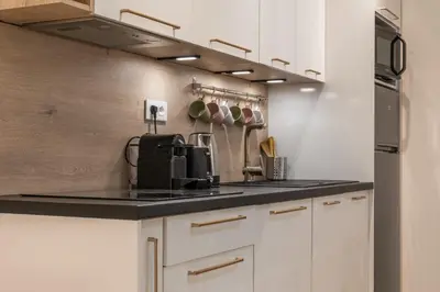 a kitchen with white cabinets and a black counter top at Upscale 3-room apartment 300m from the beaches in Cannes