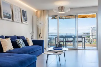 a living room with a blue couch and a table at 3-bedroom apartment sea view terrace and parking in Cannes