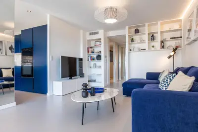 a living room with a blue couch and a table at 3-bedroom apartment sea view terrace and parking in Cannes