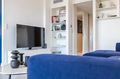 a living room with a blue couch and a tv at 3-bedroom apartment sea view terrace and parking in Cannes