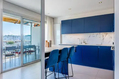 a kitchen with blue cabinets and blue bar stools at 3-bedroom apartment sea view terrace and parking in Cannes
