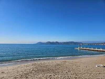 a beach with a pier and the ocean at Sweet Azur - Host Provence in Le Cannet