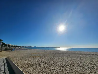 a sandy beach with the sun in the sky at Sweet Azur - Host Provence in Le Cannet