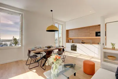 a living room with a table and a kitchen at IMMOGROOM - Appartements luxueux - 2min du Palais - Vue mer - Clim in Cannes