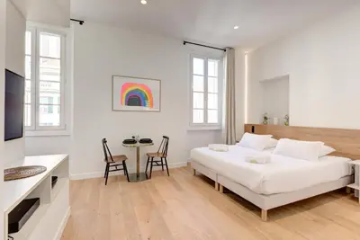 a white bedroom with a bed and a table at IMMOGROOM - Appartements luxueux - 2min du Palais - Vue mer - Clim in Cannes