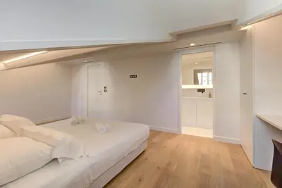 a white bedroom with a bed and a mirror at IMMOGROOM - Appartements luxueux - 2min du Palais - Vue mer - Clim in Cannes