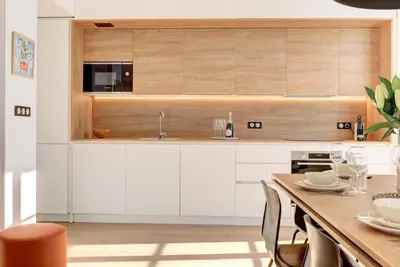 a kitchen with white cabinets and a wooden table at IMMOGROOM - Appartements luxueux - 2min du Palais - Vue mer - Clim in Cannes