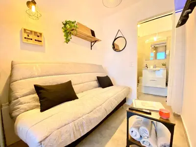 a white couch in a small room with a table at Mini-Studio Le Cormoran By SCLS Locations in Cannes