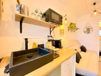 a kitchen with a sink in a room with a couch at Mini-Studio Le Cormoran By SCLS Locations in Cannes