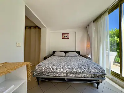 a bedroom with a bed and a large window at Les Jardins de Lérins By SCLS Locations in Cannes