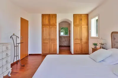 a bedroom with a large white bed and wooden cabinets at 10mn de Cannes, villa entière de 150m2. in Le Cannet
