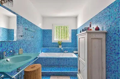 a blue tiled bathroom with a tub and a sink at 10mn de Cannes, villa entière de 150m2. in Le Cannet