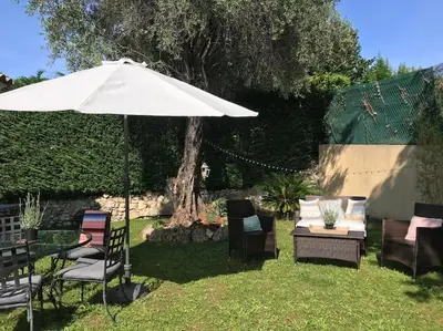 a patio with an umbrella and chairs and a table at 10mn de Cannes, villa entière de 150m2. in Le Cannet