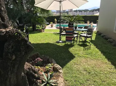 a table and chairs with an umbrella in a yard at 10mn de Cannes, villa entière de 150m2. in Le Cannet