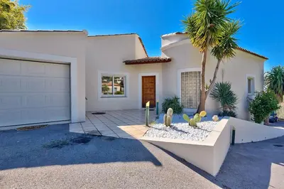 a white house with a palm tree in front of it at 10mn de Cannes, villa entière de 150m2. in Le Cannet
