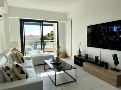 a living room with a white couch and a tv at AGENCIA Superbe appartement Le Bellevue in Cannes