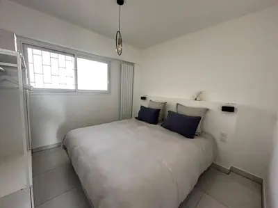 a white bedroom with a large bed with blue pillows at AGENCIA Superbe appartement Le Bellevue in Cannes