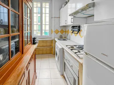 a kitchen with white cabinets and a stove top oven at Chic Cannois Proche de la Croisette in Cannes