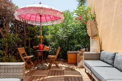 a patio with a table and a pink umbrella at LA VILLA BALI A CANNES in Cannes