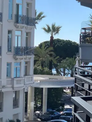 a white building with cars parked in a parking lot at My Ty Croisette Martinez YourHostHelper in Cannes
