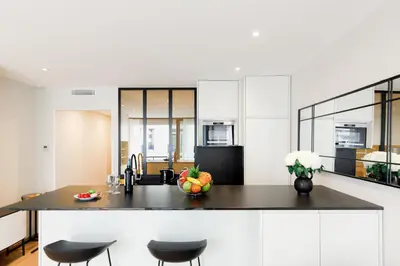 a kitchen with white cabinets and a black counter top at My Ty Croisette Martinez YourHostHelper in Cannes