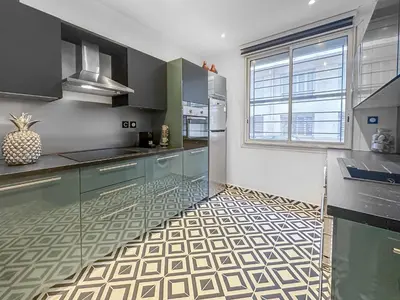 a kitchen with blue cabinets and a tile floor at La Perle de Cannes in Cannes