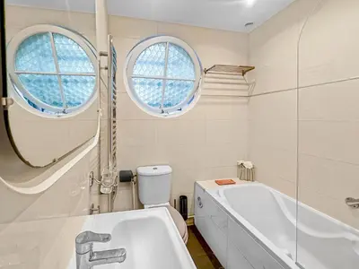 a bathroom with a tub and a toilet and two windows at La Perle de Cannes in Cannes