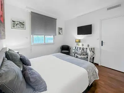 a white bedroom with a bed and a television at La Perle de Cannes in Cannes