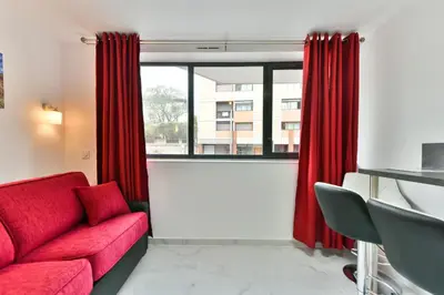 a living room with a red couch and a window at Le Coquillage - 200 mètres de la Plage in Cannes