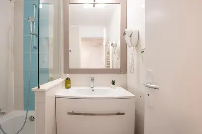 a white bathroom with a sink and a shower at Le Coquillage - 200 mètres de la Plage in Cannes