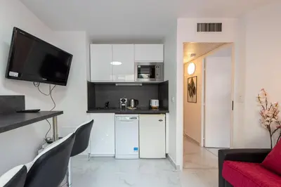 a kitchen with white cabinets and a red couch at Le Coquillage - 200 mètres de la Plage in Cannes
