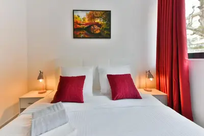 a bedroom with a white bed with two red pillows at Le Coquillage - 200 mètres de la Plage in Cannes