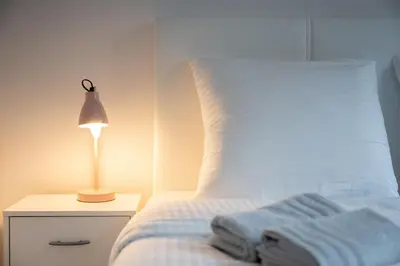 a bed with a white pillow and a lamp on a night stand at Le Coquillage - 200 mètres de la Plage in Cannes