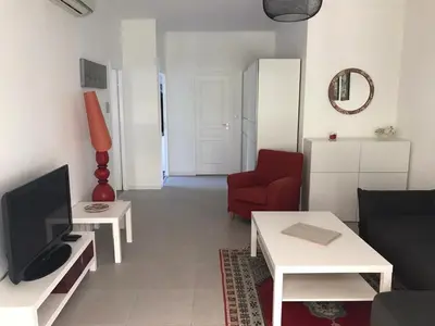 a living room with a tv and a red chair at Appartement au cœur de Cannes in Cannes