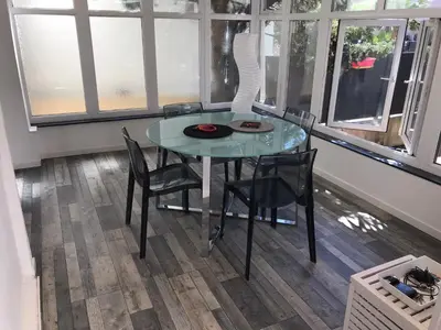 a glass table and chairs in a room with windows at Appartement au cœur de Cannes in Cannes