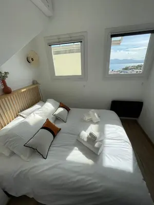 a large white bed in a bedroom with two windows at Duplex en bord de mer avec piscine et parking in Cannes
