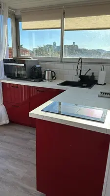 a kitchen with red cabinets and a sink and a window at Toits du vieux port in Cannes