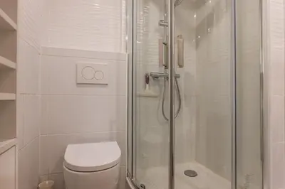 a white bathroom with a shower and a toilet at 3-Br Apartment Terrace steps from Beaches in Cannes