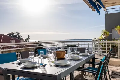 a table on a balcony with a view of the ocean at 3-Br Apartment Terrace steps from Beaches in Cannes