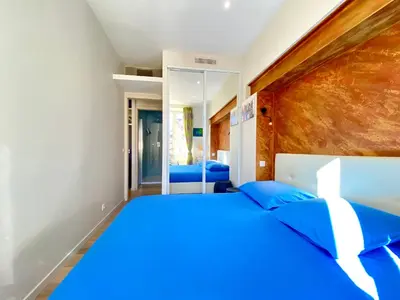 a bedroom with a large bed with blue pillows at Le 74 By SCLS Locations in Cannes